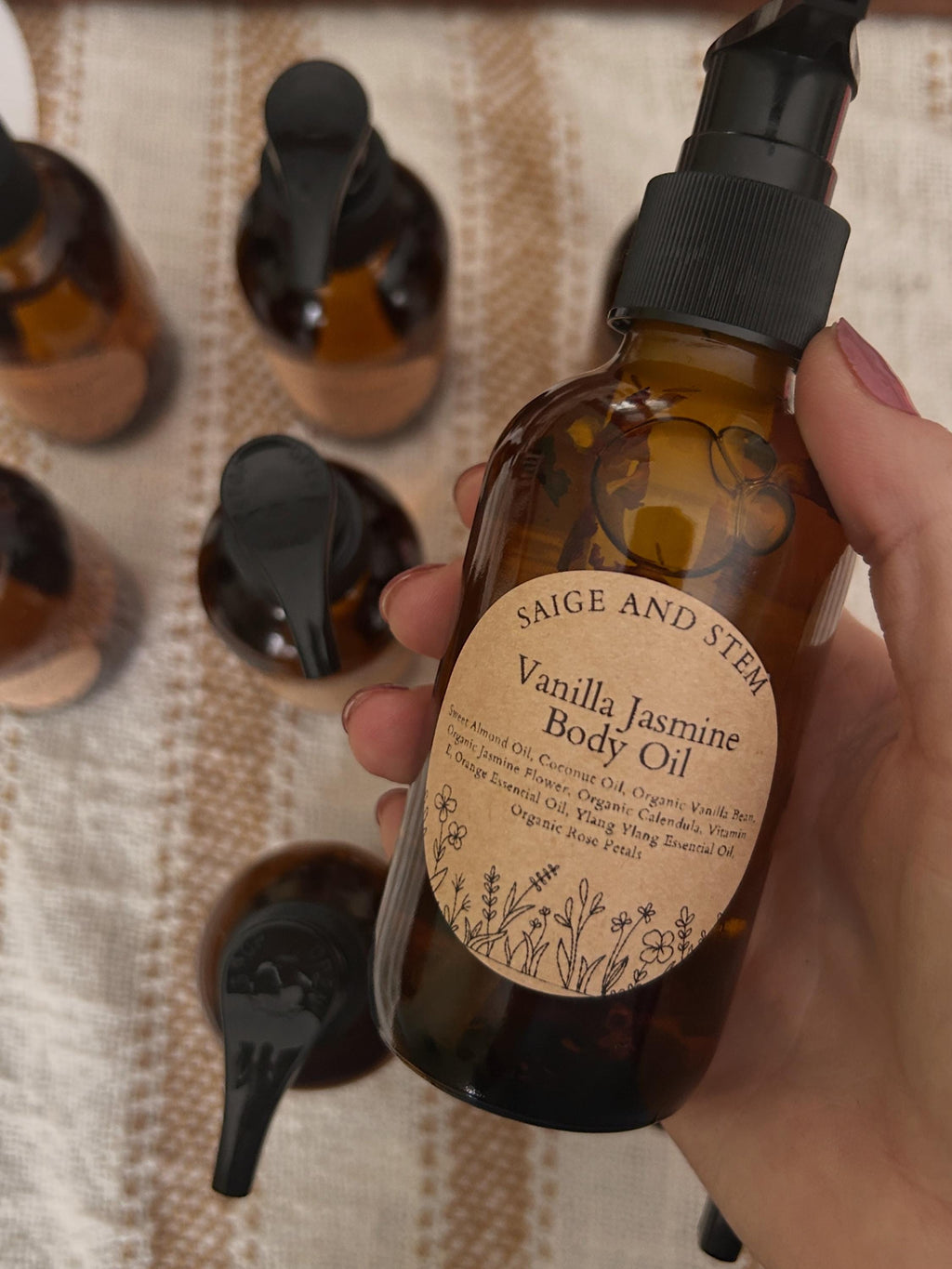 Vanilla Jasmine Body Oil in amber glass bottle with floral label, featuring calendula and coconut oil.