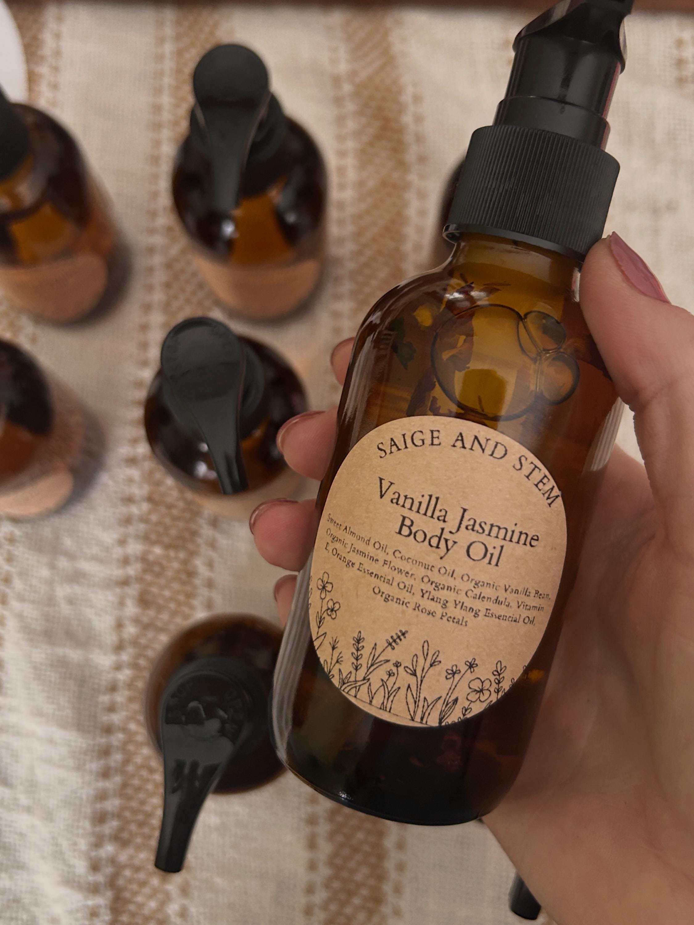 Vanilla Jasmine Body Oil in amber glass bottle with floral label, featuring calendula and coconut oil.