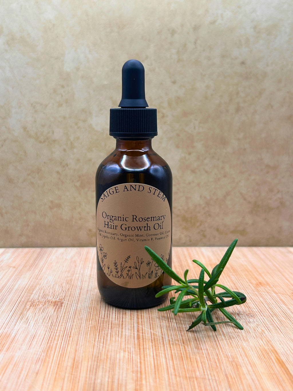 Rosemary Hair Growth Oil in a brown glass bottle with a dropper and a sprig of fresh rosemary.